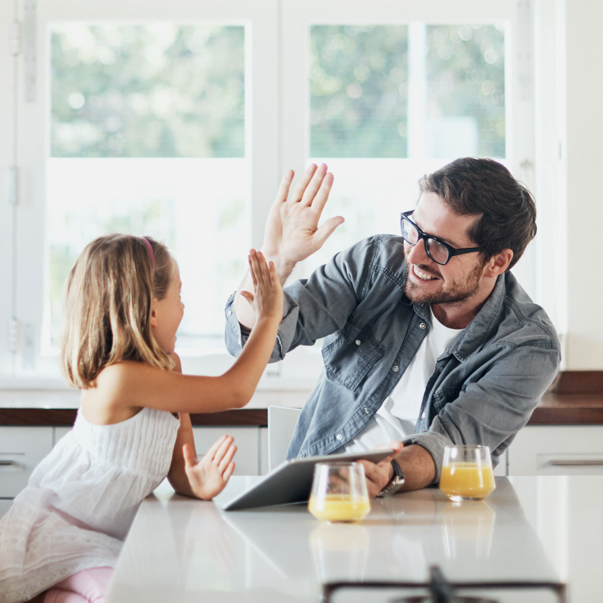 Father and daughter high fiving in a kitchen
