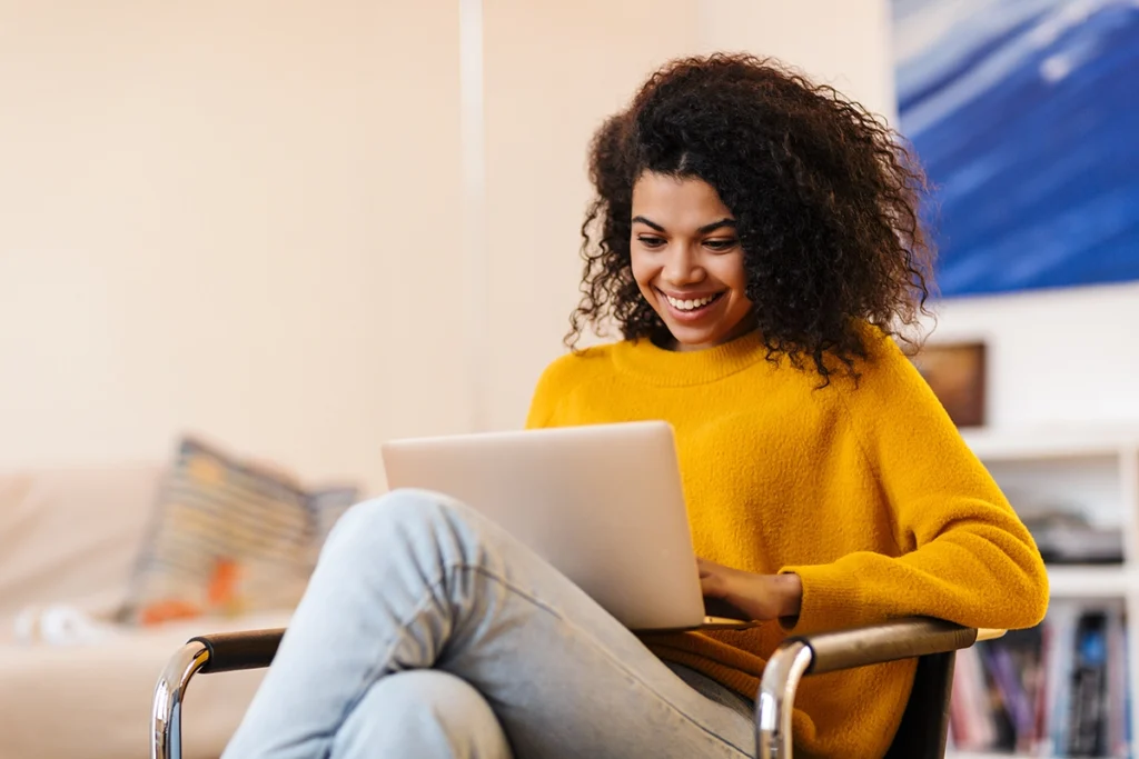 Young woman sitting in a chair with laptop in her lap